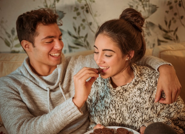 Hombre feliz alimentando a mujer con dulces