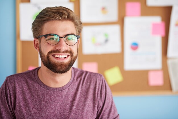 Hombre feliz con anteojos sonriendo en la oficina