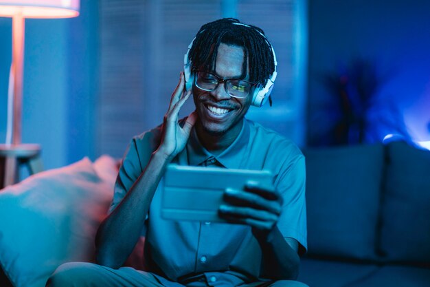 Hombre feliz en casa con tableta y auriculares