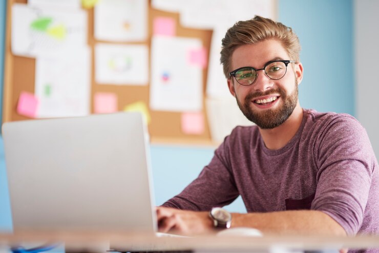 Foto gratuito hombre feliz con computadora portátil en la oficina