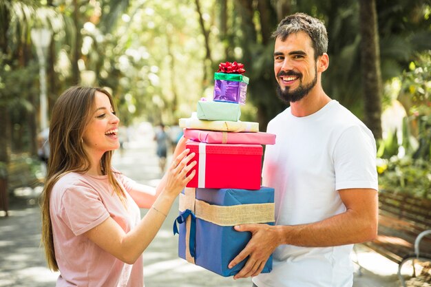 Hombre feliz dando pila de regalos a su novia