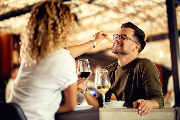 Foto gratuita hombre feliz divirtiéndose mientras su novia lo alimenta en un restaurante