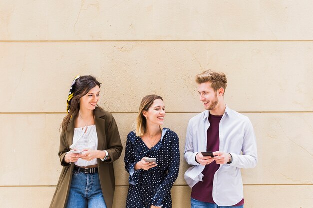 Hombre feliz con dos amigas sosteniendo teléfono móvil