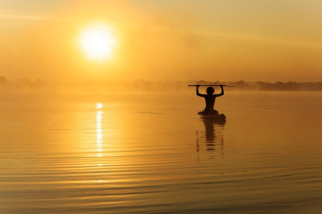 Hombre feliz entrenando en paddle board a la hora de la mañana