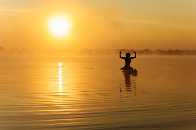 Hombre feliz entrenando en paddle board a la hora de la mañana