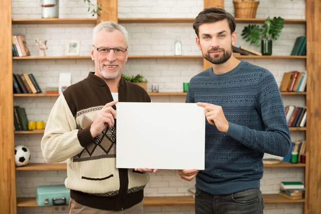 Hombre feliz envejecido y chico sonriente joven que sostiene el papel