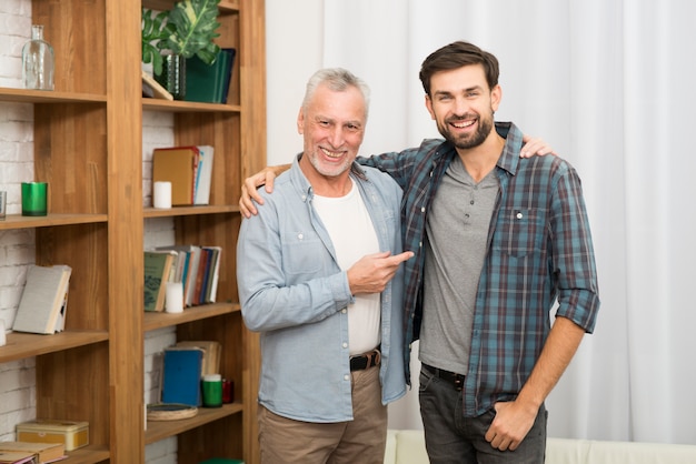 Foto gratuita hombre feliz envejecido que señala y que abraza con el individuo sonriente joven en sitio