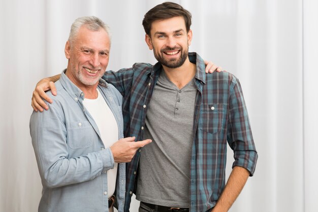 Hombre feliz envejecido que señala y que abraza con el individuo sonriente joven