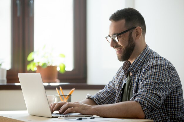 Hombre feliz escribiendo correo positivo al cliente