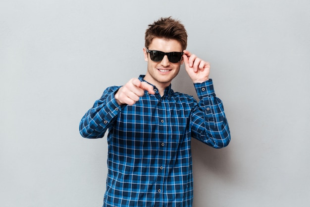 Hombre feliz con gafas de sol apuntando.