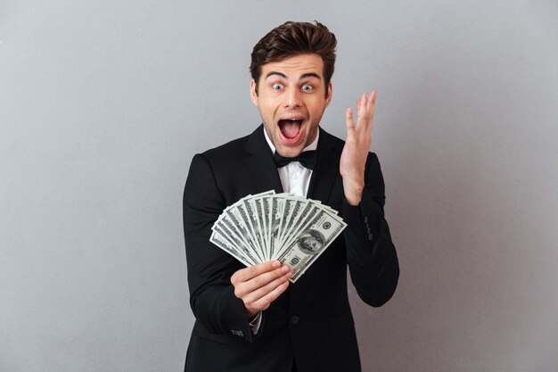 Hombre feliz gritando en traje oficial con dinero.