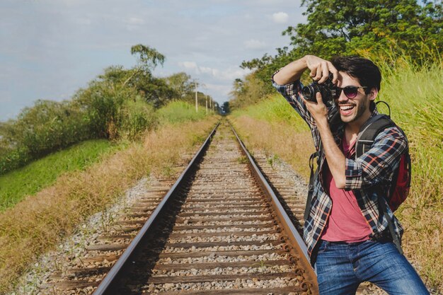 Hombre feliz haciendo una foto en vías de tren