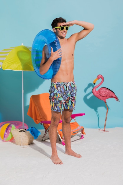 Hombre feliz joven en las gafas de sol que sostienen el tubo y que miran lejos