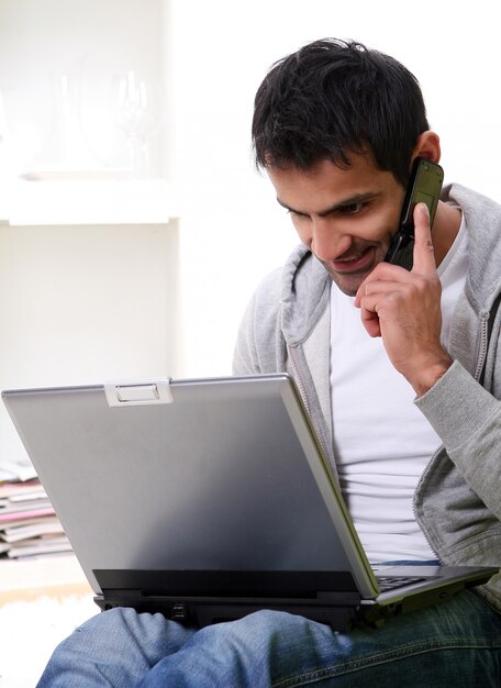 Hombre feliz y joven con laptop y teléfono