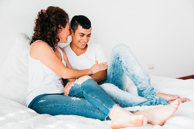 Foto gratuita hombre feliz joven y mujer que se sientan en cama