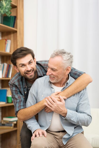 Hombre feliz joven que abraza al hombre envejecido