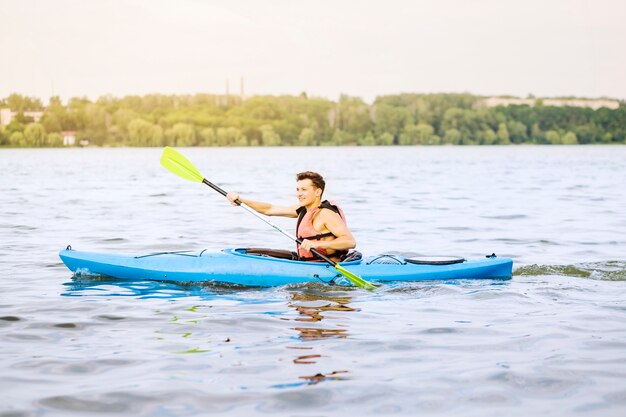 Hombre feliz en kayak en el agua ondulada