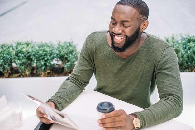 Foto gratuita hombre feliz leyendo periódico en café