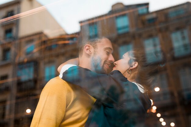 Hombre feliz y mujer abrazándose en el restaurante cerca de la ventana