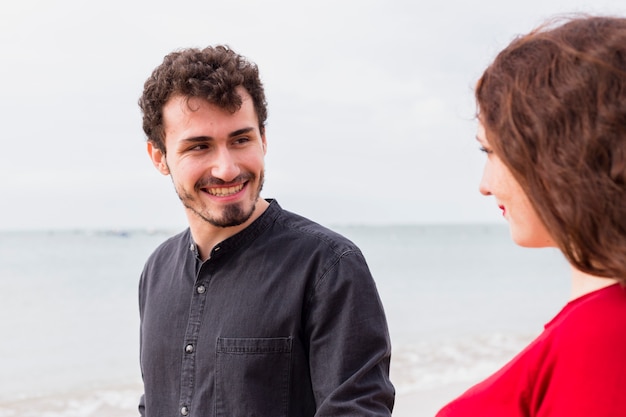 Hombre feliz con mujer en la orilla del mar