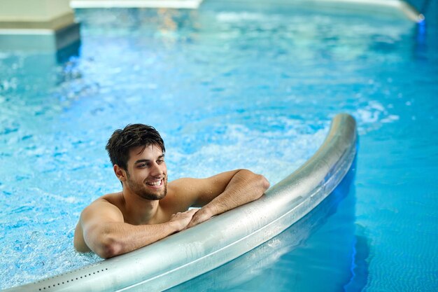 Hombre feliz pasando un día en el spa y disfrutando en la piscina