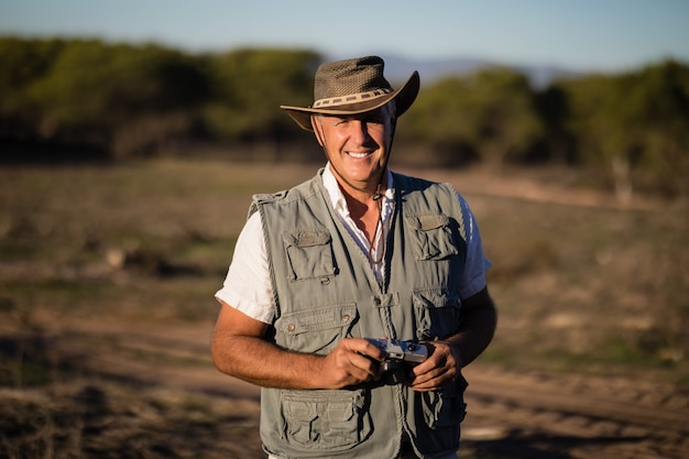 Hombre feliz de pie con la cámara durante las vacaciones de safari