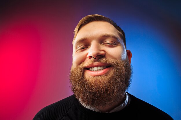 Hombre feliz que se coloca y que sonríe aislado en estudio rosado.