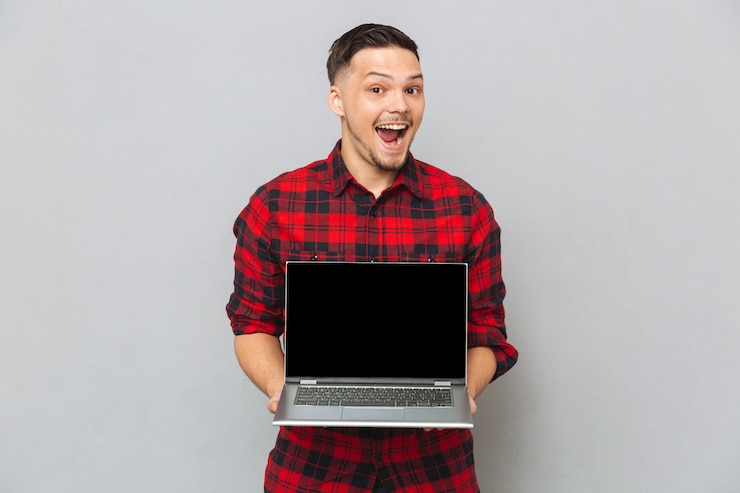 Foto gratuito hombre feliz que muestra la pantalla de la computadora portátil en la cámara