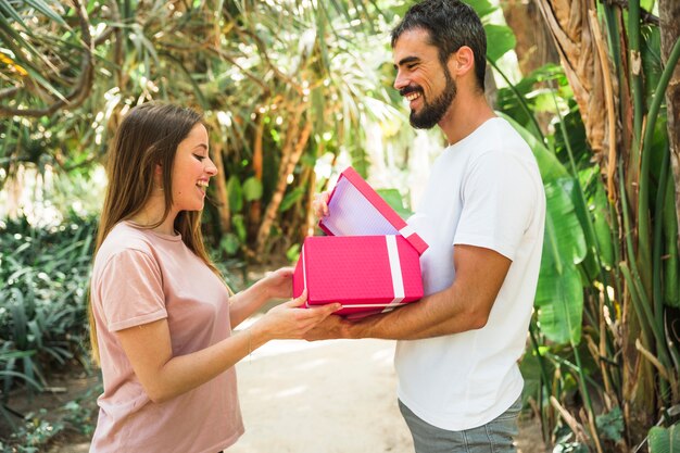 Hombre feliz que muestra el regalo a su novia en el parque