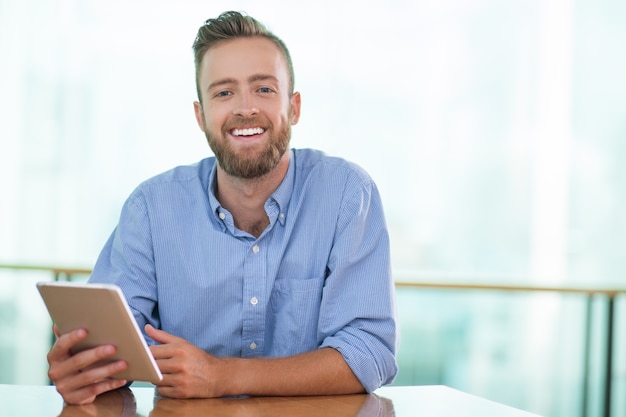 El hombre feliz que se sienta en el vector del café y que usa la tablilla