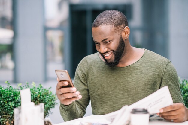 Hombre feliz que usa smartphone en café