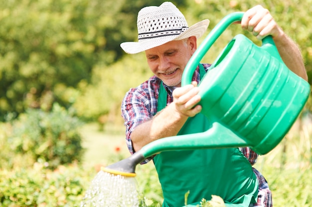 Hombre feliz regando sus plantas en verano