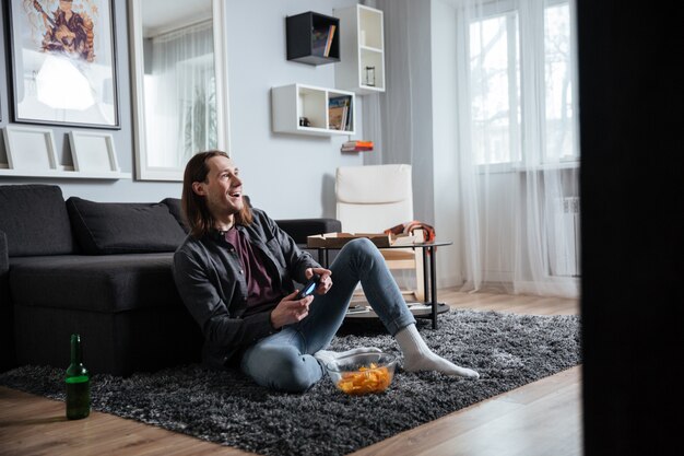 Hombre feliz sentado en casa en casa jugar con joystick