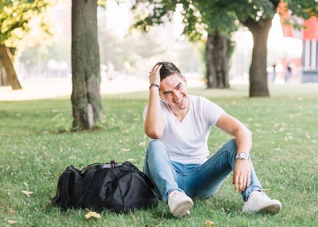 Foto gratuita hombre feliz sentado en el césped en el parque