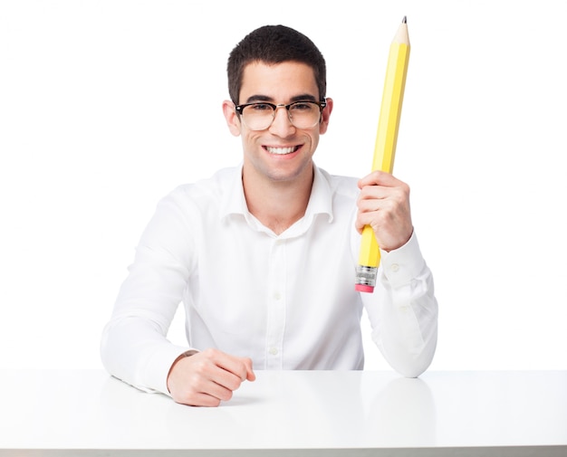 Hombre feliz sentado y sujetando un lápiz grande