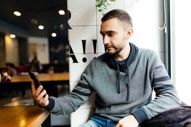 Hombre feliz con smartphone en cafetería moderna