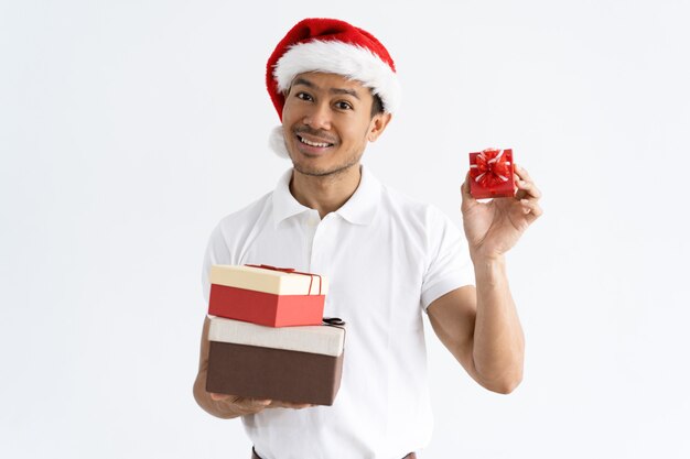 Hombre feliz con sombrero de Santa y mostrando cajas de regalo pequeñas y grandes