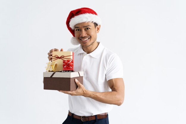 Hombre feliz con sombrero de Santa y mostrando cajas de regalo