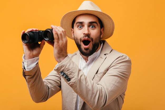 Hombre feliz con sombrero y traje beige con binoculares