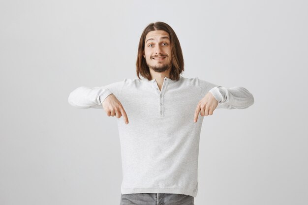 Hombre feliz sonriente apuntando con el dedo hacia abajo