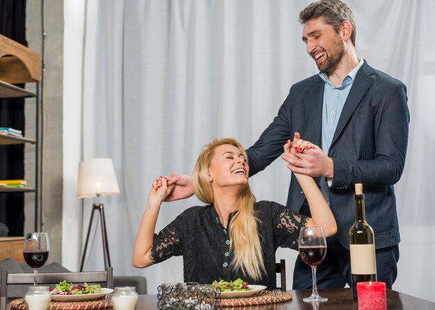 Hombre feliz sosteniendo las manos de mujer alegre en la mesa