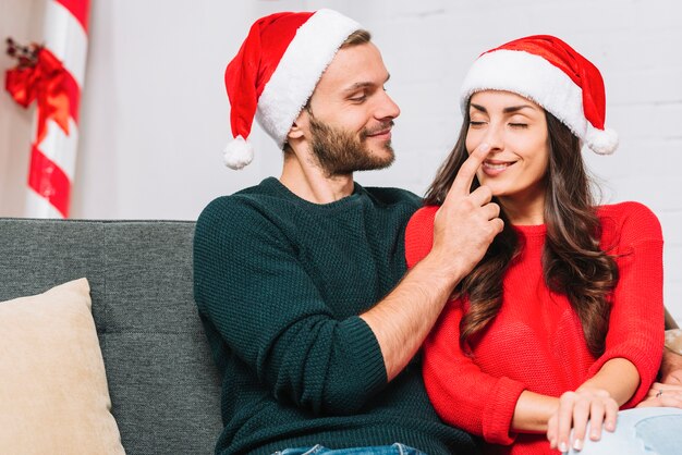 Hombre feliz sosteniendo la nariz de la mujer en el sofá