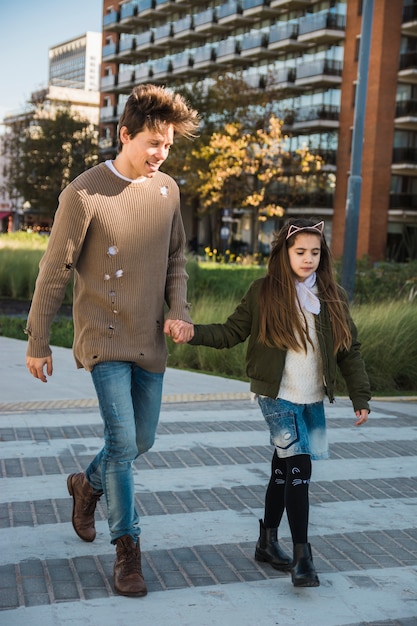 Hombre feliz con su hija caminando juntos en el pavimento