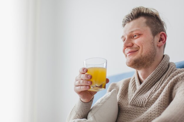 Hombre feliz sujetando un vaso con zumo de naranja