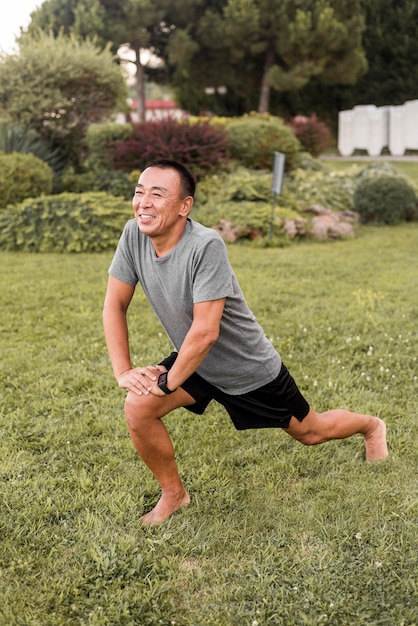 Hombre feliz de tiro completo que se extiende en la naturaleza