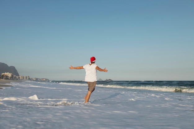 Hombre feliz de tiro lejano en la playa