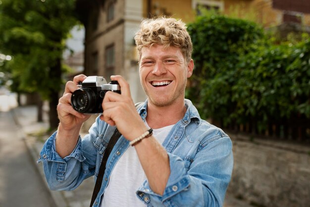 Hombre feliz de tiro medio sosteniendo la cámara