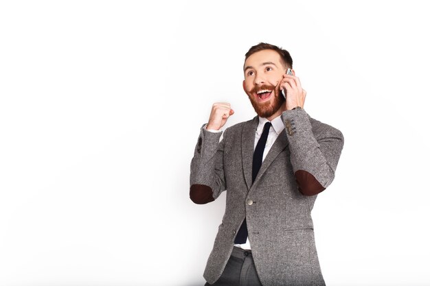 Hombre feliz en traje gris habla por teléfono