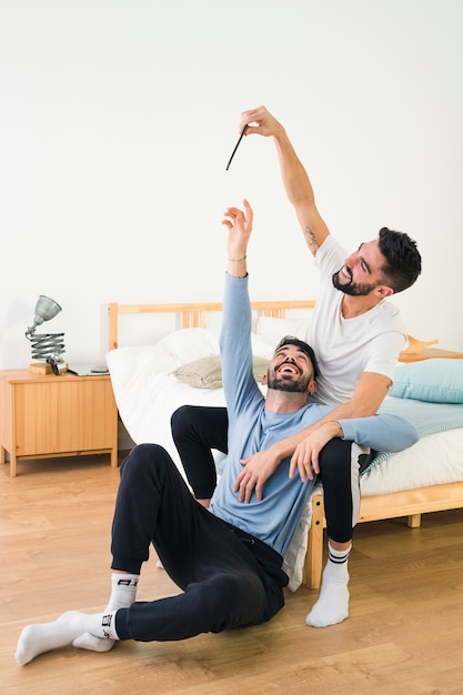 Hombre feliz tratando de atrapar la pluma de su novio en casa