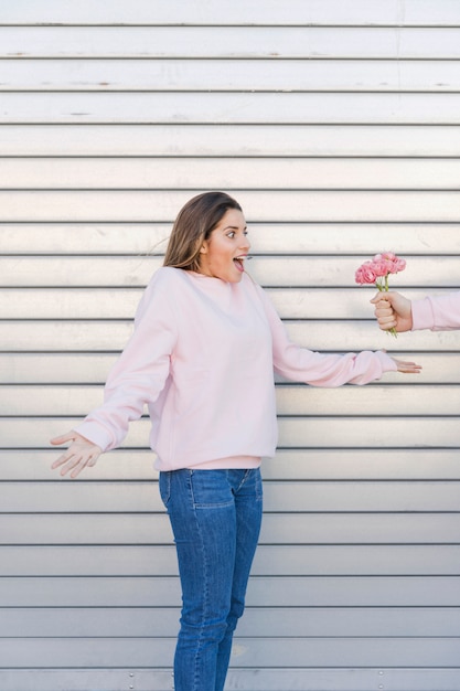 Hombre con flores cerca de mujer sorprendida